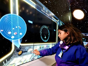 Yasmina, 8, plays with the giant interactive screen projecting the latest exhibit, Space, at the Stanley A. Milner Library.