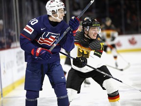 Lane Hutson (20) of Team USA is checked by Luca Hauf (17) of Team Germany in their quarter-final game at the 2023 IIHF world junior championships at Avenir Centre on Jan, 2, 2023, in Moncton, N.B.