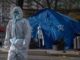 A epidemic control worker wears PPE to prevent the spread of COVID-19 as he looks out from inside a tent in an area where communities are in lockdown on November 29, 2022 in Beijing, China.