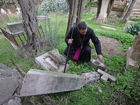 Hosam Naoum, archbishop and caretaker of the Protestant cemetery, inspects vandalised graves on Mount Zion outside Jerusalem's Old City on January 4, 2023.
