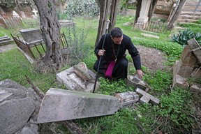 Hosam Naoum, archbishop and caretaker of the Protestant cemetery, inspects vandalised graves on Mount Zion outside Jerusalem's Old City on January 4, 2023.