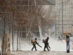 Crews clear the snow covered sidewalks around the Law Courts building in downtown Edmonton, Friday, Jan. 27, 2023.