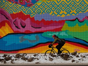 A cyclist makes their way along a bike lane on 105 Avenue near 111 Street in Edmonton, Monday, Jan. 30, 2023. A mural by Sofia Lukie is visible in the background.