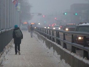 Pedestrians make their way through a heavy fog as they cross the Mill Creek Bridge, in Edmonton on Wednesday, Jan. 11, 2023.
