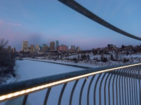 The early morning downtown city skyline can be seen through the illuminated handrails of the Tawatinâ Bridge on Thursday, Dec. 8, 2022, in Edmonton.