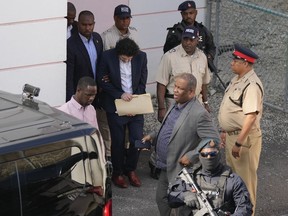 FTX founder Sam Bankman-Fried, center, is escorted out of Magistrate Court into a Corrections van, following a hearing in Nassau, Bahamas, Monday, Dec. 19, 2022.