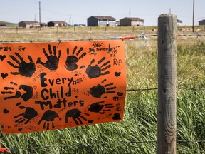 A sign commemorating victims of residential schools is attached to a fence line in front of homes east of Calgary near Gliechen, Alta., Tuesday, June 29, 2021. A new report from a group looking into children that died and went missing at an Alberta residential school says unpasteurized milk was responsible for the deaths of Indigenous children at the institution.