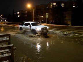 A motorist drives through a flooded Rossdale Road near 102 Street in Edmonton Monday, January 30, 2023.