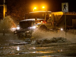 A city of Edmonton plow named Amarsleet Snowhi makes its way through a flooded Rossdale Road near 102 Street on Monday, Jan. 30, 2023.