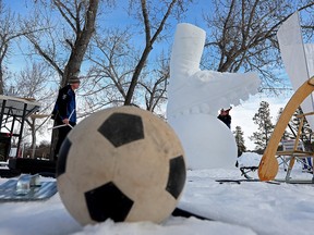 Pemahat salju Brian McArthur dan Michael Decaire mengerjakan patung salju dari gerigi sepak bola dan bola sepak selama Silver Skate Festival di Edmonton's Hawrelak Park, Minggu 12 Februari 2023.