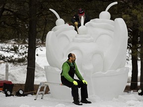 Christian Denis (atas) dan Randall Fraser mengerjakan patung salju raksasa yang dibelah pisang selama Festival Silver Skate di Edmonton's Hawrelak Park, Minggu 12 Februari 2023.