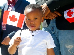 Brian Egbe waves a flag in Calgary during a first in-person citizenship ceremony at the BMO Amphitheatre on Stampede Park on July 11, 2022. Darren Makowichuk/Postmedia