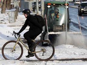 Seorang pengendara sepeda berjalan di sepanjang jalur sepeda 83 Avenue saat kru City of Edmonton membersihkan trotoar di sepanjang 109 Street, Rabu, 8 Februari 2023.