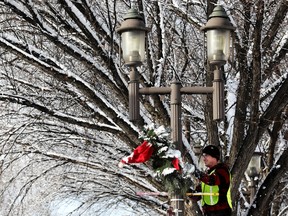 Nick Deroche bersama Zocalo, melepas dekorasi Natal dari tiang lampu di sepanjang Whyte Avenue Edmonton, Rabu, 8 Februari 2023.