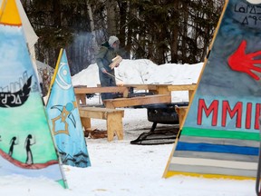Lisa Meraw starts warming fires in preparation for the first night of the the Flying Canoë Volant festival in Edmonton's Mill Creek Ravine, Thursday, Feb. 2, 2023. The festival runs Feb. 1-4.
