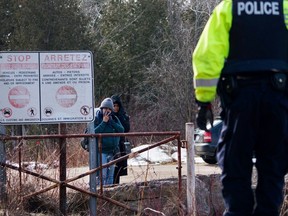 Two people listen to a Royal Canadian Mounted Police officer as they attempt to illegally cross into Canada from Perry Mills, N.Y., near Hemmingford, Quebec.