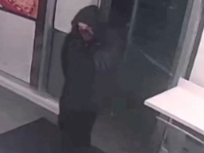The suspect in a north Edmonton shooting is described as wearing a black bulky coat with a hooded sweater underneath, black pants/jeans that are tight around the calf, black shoes or boots and a multi-coloured face covering. The suspect entered a pizza restaurant on Sunday March 12, 2023, carrying a firearm and shot a 55-year-old male employee, then fled the scene.