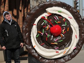 A pedestrians stops to check out a giant cookie along 104 street South of 104 Avenue in Edmonton, Wednesday,k March 22, 2023. While there is no signage on the cookie a QR code does direct visitors to Crumbl Cookies Canada.