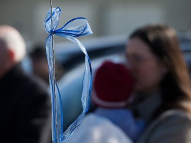 A blue ribbon is visible on a vehicle as Edmontonians line the street around the Serenity Funeral Home as a procession arrives with the bodies of Const. Travis Jordan and Const. Brett Ryan, in Edmonton Tuesday March 21, 2023.