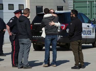 People comfort each other outside the Serenity Funeral Home as a procession arrives with the bodies of Const. Travis Jordan and Const. Brett Ryan, in Edmonton Tuesday March 21, 2023.