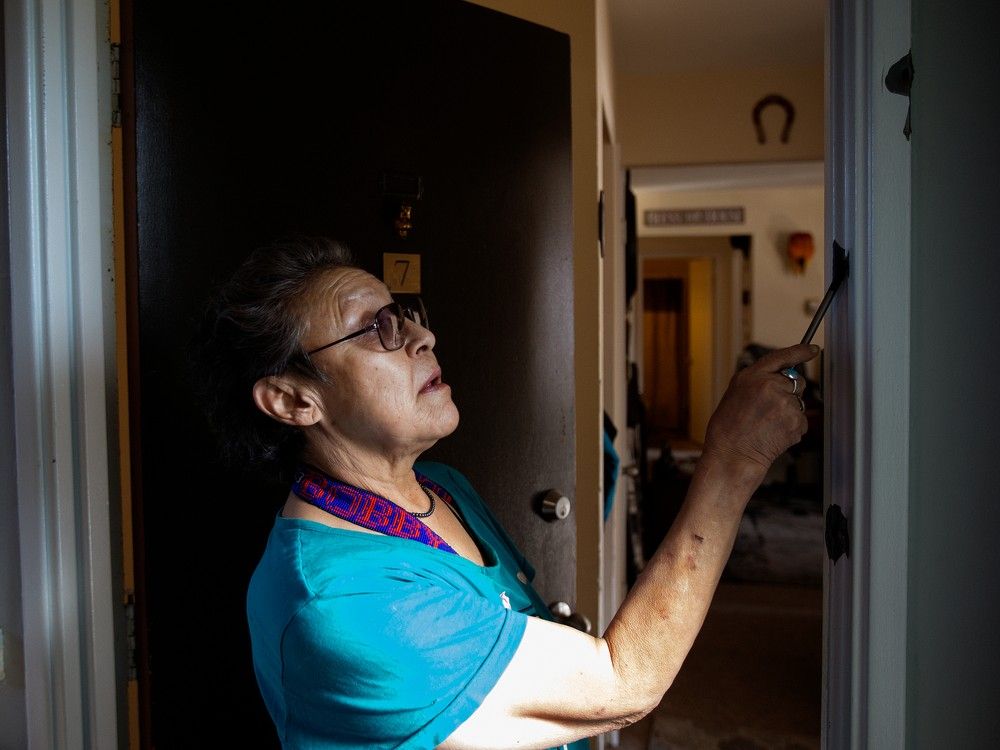 Darlene Blyan looks at the six bullet holes visible in the doorway of her apartment on Monday, March 20, 2023, following the shooting deaths of Const. Travis Jordan and Const. Brett Ryan last Thursday. Blyan lives across the hall from the apartment where the two officers responded to a family violence call.
