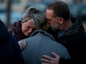 The family of Const. Brett Ryan comfort each other as they take part in a vigil outside the West Division Edmonton police station in Edmonton on Friday, March 17, 2023. Const. Travis Jordan and Const. Brett Ryan were both killed in the line of duty on March 16, 2023. Both officers worked out of the West Division station.