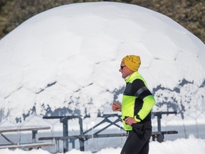 A runner glides past dome shaped shelter in Hawrelak Park harbouring the fresh snowfall from overnight on March 1, 2023.