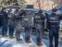 Petugas polisi menghormati rekan mereka yang gugur saat mereka diangkut ke kantor pemeriksa medis dengan pengawalan polisi, pemadam kebakaran, dan EMS pada 16 Maret 2023 di Edmonton.  Dua anggota EPS tewas dalam menjalankan tugas setelah menanggapi panggilan domestik pada hari sebelumnya. 