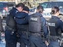 Petugas polisi menghormati rekan mereka yang gugur saat mereka diangkut ke kantor pemeriksa medis dengan pengawalan polisi, pemadam kebakaran, dan EMS pada 16 Maret 2023 di Edmonton.  Dua anggota EPS tewas dalam menjalankan tugas setelah menanggapi panggilan domestik pada hari sebelumnya. 