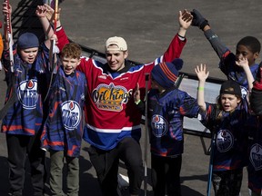 Edmonton Oil Kings forward Cole Miller poses for a photo with kids taking part in the street hockey tournament during the NHL Street Festival outside Rogers Place in Edmonton on Saturday, April 15, 2023.
