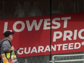 A pedestrian walks past a store's signage stating "Lowest Price Guaranteed" on Parliament Street in Toronto.
