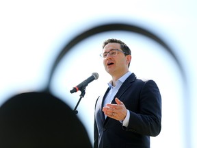 Pierre Poilievre, Leader of the Conservative Party of Canada and the Official Opposition, is framed by the armrest of a park bench as he speaks to the media during a stop in Edmonton, Thursday, April 13, 2023.