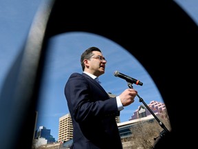 Conservative Party of Canada Leader Pierre Poilievre is framed by the armrest of a park bench as he speaks to the media during a stop in Edmonton on Thursday, April 13, 2023.