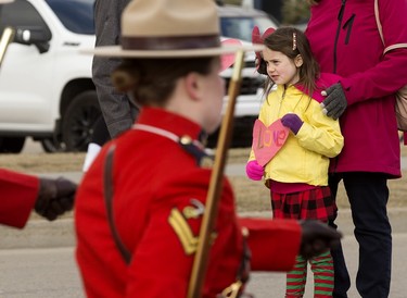 A young girl holds a paper heart as she watches the regimental funeral procession for Const. Harvinder Singh Dhami in Sherwood Park, Alta., Thursday April 20, 2023.
