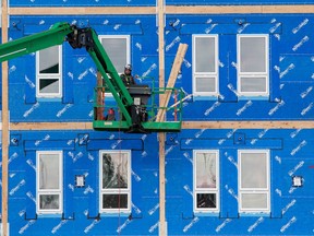 A constriction worker works on the outside of a prefabricated supportive housing complex being built for the City of Edmonton at 6210 Terrace Road on Wednesday, Feb. 9, 2022 in Edmonton.  The building was designed by GEC Architecture.