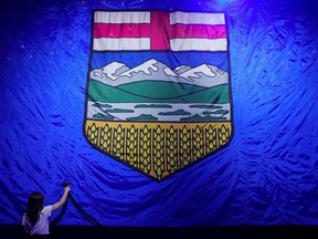 A worker irons a giant Alberta flag while getting the stage ready for the United Conservative Party provincial election night party in Calgary on May 29, 2023.