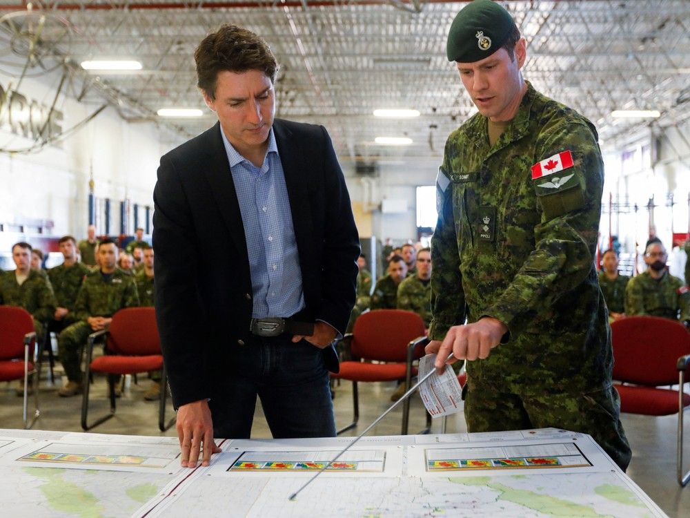Prime Minister Justin Trudeau is briefed by Canadian Forces Col. Ben Schmidt at CFB Edmonton, who are assisting in wildfire relief efforts, in Sturgeon County on Monday, May 15, 2023. 