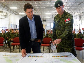 Prime Minister Justin Trudeau is briefed by Canadian Forces Col. Ben Schmidt at CFB Edmonton, who are assisting in wildfire relief efforts, in Sturgeon County on Monday, May 15, 2023.