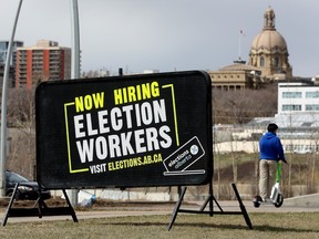 The Alberta legislature is visible behind a sign in Edmonton's river valley advertising the hiring of election workers on April 26, 2023, ahead of the May 29 Alberta provincial election.