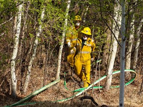 Firefighters work to stop a fire near Graydon Hill Blvd and Graydon Hill LInk from getting to near-by townhomes on Thursday, May 4, 2023 in Edmonton.