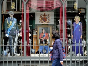 A woman walks by a storefront featuring King Charles III in London on Tuesday, May 2, 2023. Crowds from all over the world -- including Canada -- were beginning to gather in London ahead of the coronation of King Charles.
