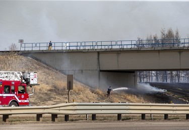 Firefighters fight a fire that burns under train tracks on the Anthony Henday on Monday, May 1, 2023 in Edmonton.
