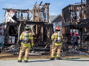 Firefighters put out hotspots in a fire that destroyed three homes on Stevens Crescent on Monday, May 1, 2023, in Edmonton.