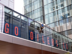 Window cleaners work on a pedway over 101 street with giant Orange letters that spell Go Oilers Go in Edmonton on May 11, 2023.