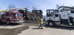 Firefighters work to put out hotspots in a fire that destroyed three homes on Stevens Crescent on Monday, May 1, 2023, in Edmonton.