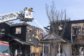 Firefighters work to put out hotspots in a fire that destroyed three homes on Stevens Crescent on Monday, May 1, 2023, in Edmonton.