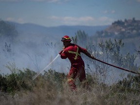 A firefighter directs water on a grass fire burning on an acreage behind a residential property in Kamloops, B.C., Monday, June 5, 2023. New Democrats are calling on the federal government to increase the tax credit for volunteer firefighters as they combat wildfires raging across the country.&ampnbsp;THE CANADIAN PRESS/Darryl Dyck