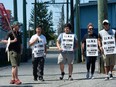 Striking port workers belonging to the International Longshore and Warehouse Union Canada walk the picket line near the Port of Vancouver's Clark Drive entrance in Vancouver July 1, 2023.