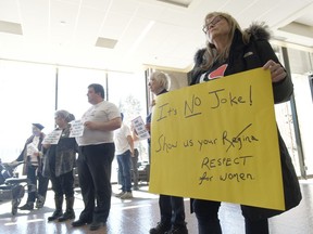 Karlene Gibson, left, holds a sign during a rally at City Hall in Regina on Wednesday, April 5, 2023. Experience Regina, the city's tourism agency, was launched in March with it posting phrases on social media that seemed to make light of the Saskatchewan capital's name rhyming with female anatomy.