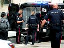 Edmonton Police Service members take a person into custody along 100 Street just north of 102 Avenue in Edmonton on Aug. 2, 2023.